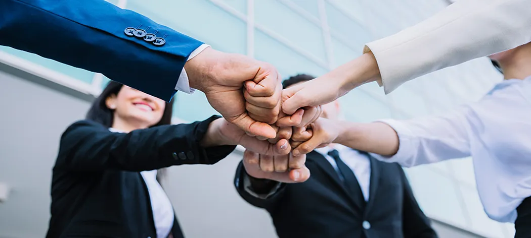 Team members joining fists together showing teamwork and collaboration